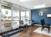 Thumbnail 3 of 31 - a living room with blue walls and a window with chairs and a table