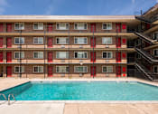 Thumbnail 12 of 31 - the pool is in front of a red brick building with a swimming pool