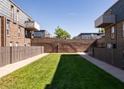 Thumbnail 25 of 39 - the yard of a building with a grass lawn and a brick retaining wall