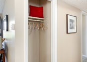 Thumbnail 8 of 39 - a closet with a red pillow and a white shelf with hangers