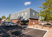 Thumbnail 32 of 39 - the exterior of a building with cars parked in a parking lot