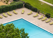Thumbnail 13 of 34 - a swimming pool with yellow lounge chairs and a fence around it