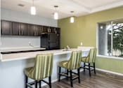 Thumbnail 25 of 34 - a kitchen with a counter and three chairs