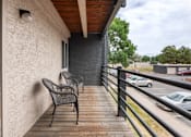 Thumbnail 10 of 34 - a balcony with two chairs and a building with a parking lot