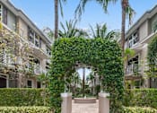Thumbnail 17 of 31 - the archway of an apartment complex with palm trees and greenery