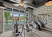 Thumbnail 23 of 31 - a gym with cardio machines and a view of the pool