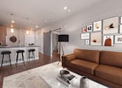 Thumbnail 5 of 39 - A living room with a brown couch and a white rug.