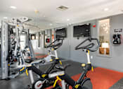 Thumbnail 26 of 43 - a gym with exercise bikes and a tv in the wall