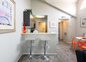 Thumbnail 25 of 87 - a bar with three stools in a living room with a kitchen and a hallway