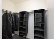 Thumbnail 13 of 43 - a walk in closet with black jackets and empty shelves