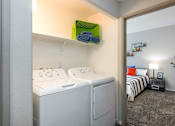 Thumbnail 19 of 54 - a laundry room with a washer and dryer and a bedroom with a bed