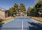 Thumbnail 47 of 54 - a tennis court with a fence around it and trees