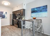 Thumbnail 7 of 47 - a kitchen with a bar with stools and a stainless steel refrigerator