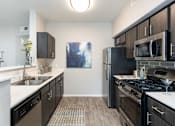 Thumbnail 8 of 47 - an empty kitchen with stainless steel appliances and wood flooring
