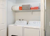 Thumbnail 11 of 36 - a white washer and dryer in a white laundry room with a shelf above