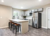 Thumbnail 26 of 36 - a kitchen with a large island with bar stools and a stainless steel refrigerator