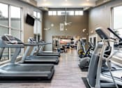 Thumbnail 21 of 36 - a gym with cardio equipment and large windows