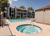 Thumbnail 18 of 36 - a swimming pool with a hot tub in front of an apartment building