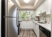 Thumbnail 18 of 42 - a white kitchen with stainless steel appliances and a window