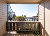 Thumbnail 10 of 38 - a balcony with a wooden bench and a view of a building and a playground