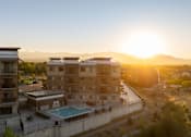 Thumbnail 39 of 42 - a building with a pool in front of a sunset