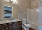 Thumbnail 6 of 12 - A bathroom with a toilet, sink, and bathtub.