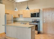 Thumbnail 1 of 16 - A kitchen with wooden cabinets and a stainless steel refrigerator, Kassenborg Apartments, Moorhead, MN