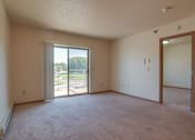 Thumbnail 8 of 16 - A room with a carpeted floor, a sliding glass door, and a mirror on the wall, Kassenborg Apartments, Moorhead, MN, 56560