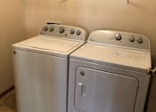Thumbnail 6 of 8 - Two front loading washing machines in a laundry room.