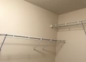 Thumbnail 5 of 8 - Empty walk-in closet with shelves and hangers.
