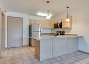 Thumbnail 4 of 16 - A kitchen with wooden cabinets and a stainless steel refrigerator, Kassenborg Apartments, Moorhead, MN, 56560
