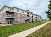 Thumbnail 1 of 8 - a large apartment complex with a grassy area in front of it at Boulder Ridge Apartments, Fargo