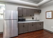 Thumbnail 10 of 17 - A kitchen with a stainless steel refrigerator and wooden floors at Courtyard Apartments on Belsly Apartments, Moorhead, Minnesota
