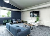 Thumbnail 11 of 17 - A room with blue couches and a television mounted on the wall at Courtyard Apartments on Belsly Apartments, Moorhead, MN, 56560