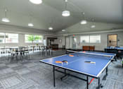 Thumbnail 14 of 17 - A ping pong table is in the middle of a room with chairs and tables at Courtyard Apartments on Belsly Apartments, Minnesota