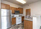 Thumbnail 3 of 17 - A kitchen with a refrigerator, microwave, oven, and sink. at Courtyard Apartments on Belsly  Apartments, Moorhead, MN