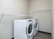 Thumbnail 7 of 13 - Two white front load washing machines in a small laundry room.