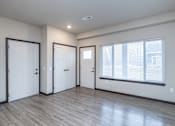 Thumbnail 3 of 13 - A room with a window, wooden floors, and white walls.