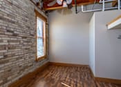 Thumbnail 9 of 16 - A room with a brick wall and wooden flooring, Kassenborg Apartments, Moorhead, Minnesota
