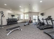 Thumbnail 8 of 12 - A spacious gym with a variety of equipment including treadmills, weights, and exercise machines.
