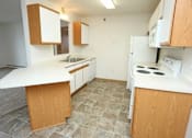 Thumbnail 2 of 6 - A kitchen with white appliances and wooden cabinets.