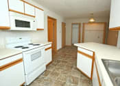 Thumbnail 1 of 6 - A kitchen with white appliances and brown cabinets.