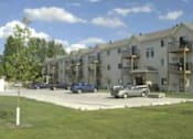 Thumbnail 6 of 6 - Apartment building with cars parked in front.