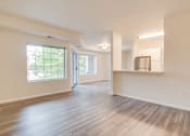 Thumbnail 4 of 8 - A spacious room with wooden floors and a kitchenette.