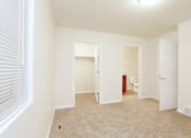 Thumbnail 4 of 10 - A white room with a carpeted floor and a window with blinds.