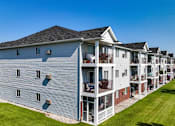 Thumbnail 7 of 8 - A row of townhouses with balconies and a clear blue sky above, at Royal Oaks Apartments, Fargo