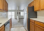 Thumbnail 2 of 9 - A kitchen with a black refrigerator and wooden cabinets.