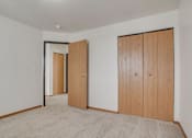 Thumbnail 6 of 9 - A room with two wooden doors and a carpeted floor.