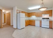 Thumbnail 7 of 11 - A kitchen with white appliances and wooden cabinets at Savanna  Apartments, St Cloud, MN