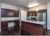 Thumbnail 2 of 10 - A kitchen with dark wood cabinets and a granite countertop.